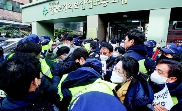 민노총 측은 압수수색을 막아서며 사무실 문에 ‘공안탄압 중단하라’는 팻말을 붙이고 경찰과 몸싸움을 벌이고 있다. (사진출처 : 민노총 트위터)
