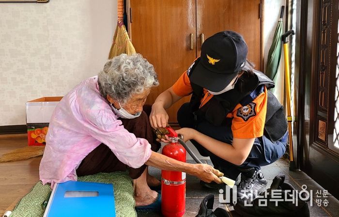 소방서 직원이 가정방문하여 소화기 사용방법을 교육하고 있다.