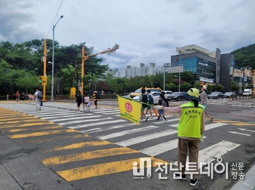 등하굣길 안전지킴이의 교통안내 지도에 따라 학생들이 안전하게 하교하고 있다.