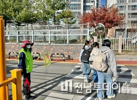 등하굣길 안전지킴이의 교통지도에 따라 학생들이 안전하게 등교하고 있다.