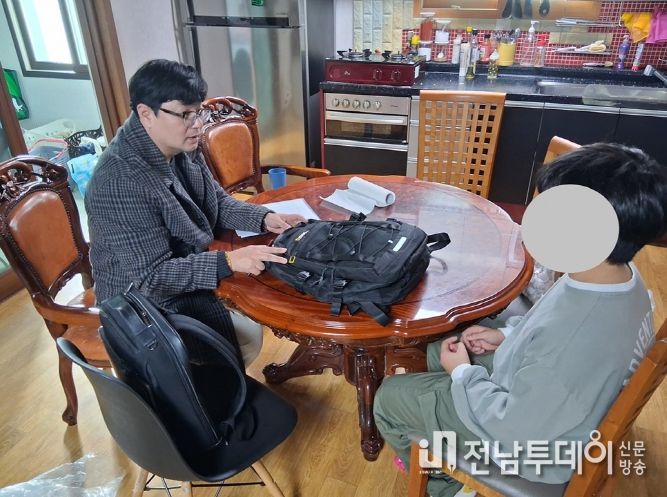 신안군 드림스타트 아동통합사례관리사가 가정 방문하여 아동에게 책가방을 전달하고 있다.